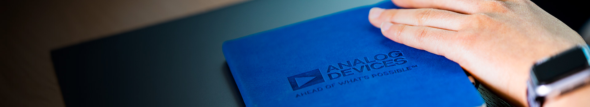 A hand touching to a book with an Analog Devices logo on it