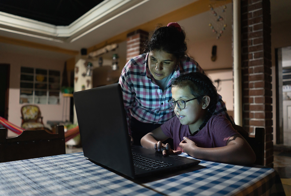 Mother and daughter looking at a laptop screen on a kitchen table.