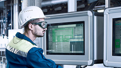 Factory worker in safety gear working at computers