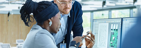Engineer talks with colleague while holding a circuit board