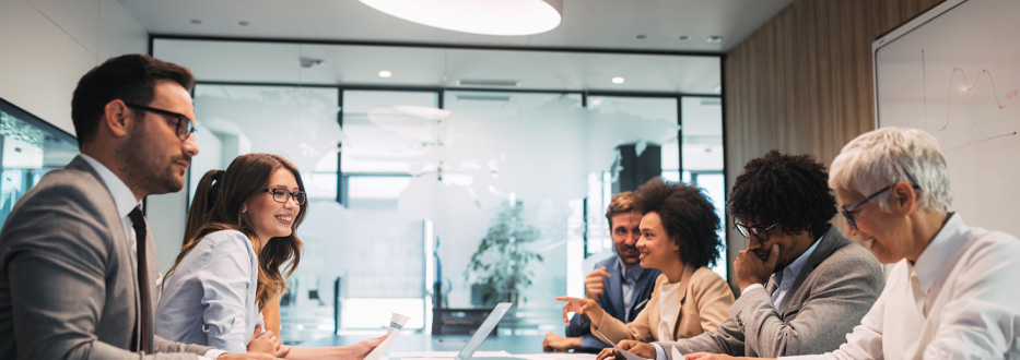A diverse group of people happily talking in a conferencing room.