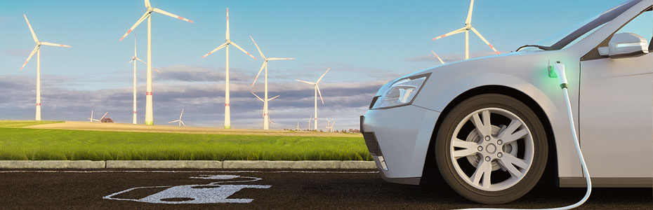 Electric car charging next to wind turbines
