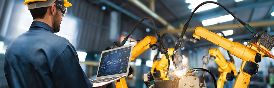 Worker standing next to industrial robots welding