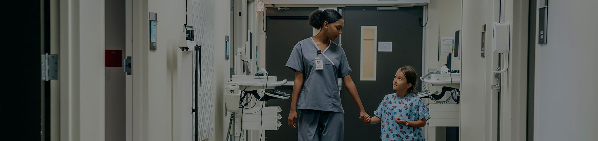 Girl and nurse walking through hospital holding hands