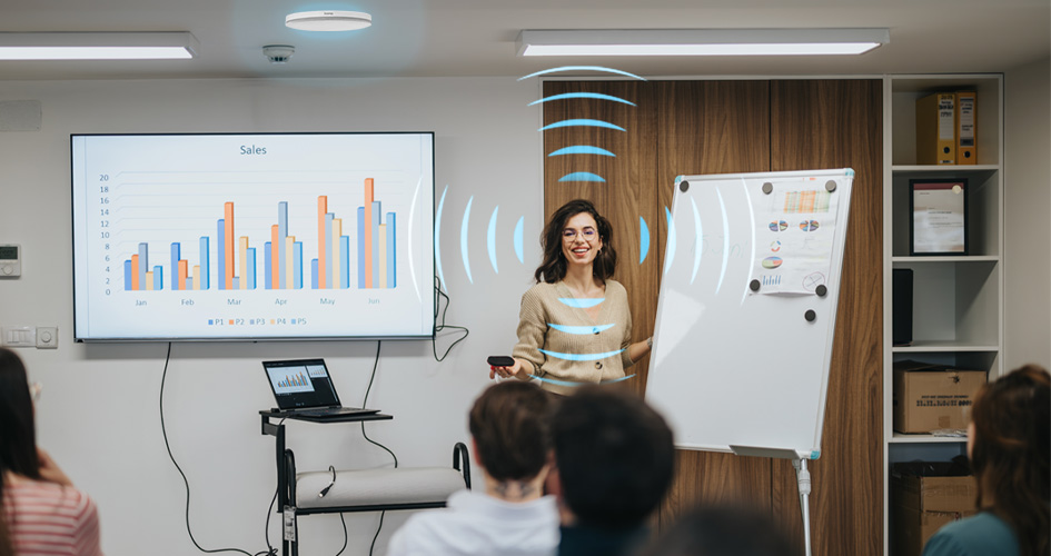 A woman with blue sound waves coming from her mouth as she's teaching a college course and a of biam speakers detecting her voice.