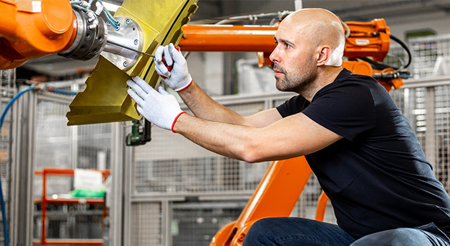Engineer repairing an automatic robot arm in automotive, smart factory