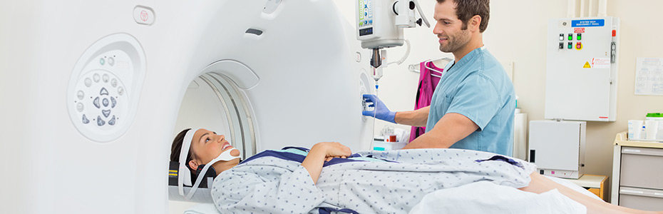 Young male nurse preparing patient for CT scan test in examination room