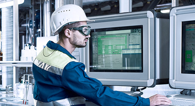 Factory worker in safety gear working at computers