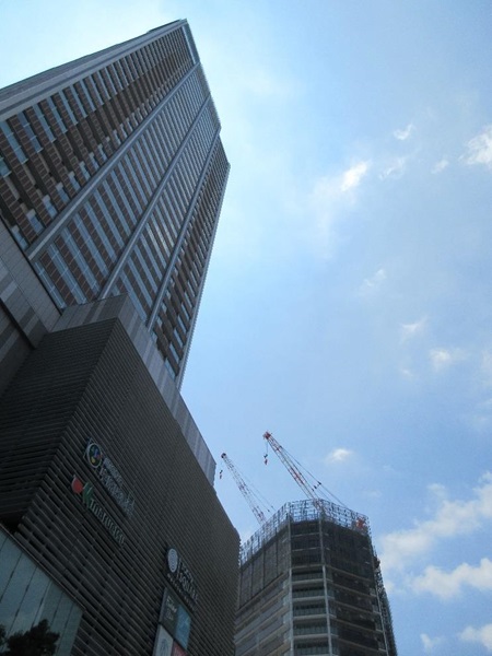 図14. 東急東横線武蔵小杉駅中央口3東急スクエア出口先(JR連絡口階段下)より撮影(左はエクラスタワー武蔵小杉。朝には運転手つき黒塗り超高級外車が玄関に停まっていることがある…。後方は2019年夏時点で建築中のKosugi 3rd Avenue The Residence)